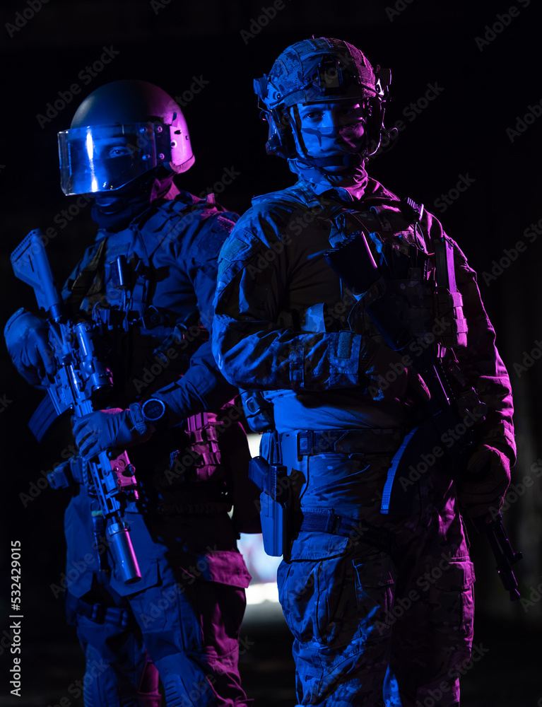 Fototapeta premium Modern warfare soldiers in dark with combat ammunition and weapons in the hands of equipped laser sights are in battle order. Mixed media. 