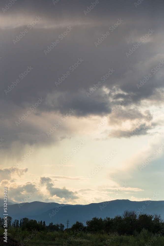 Thunderhead covers the Balkans. Downpour is approaching agricultural land. Villages, fields and forests of Bulgaria before the rain. The terrain in southern Europe. Panorama. Thunderhead covers the Balkans. Downpour is approaching agricultural land. Villages, fields and forests of Bulgaria before the rain. The terrain in southern Europe. Panorama.