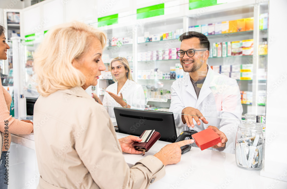 Obraz premium Pharmacist selling medications to customer in the pharmacy store.