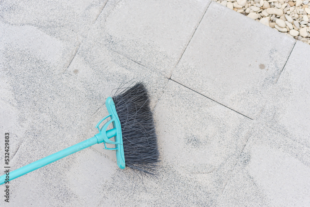 Plastic broom to fill polymeric paver sand on top of gray concrete