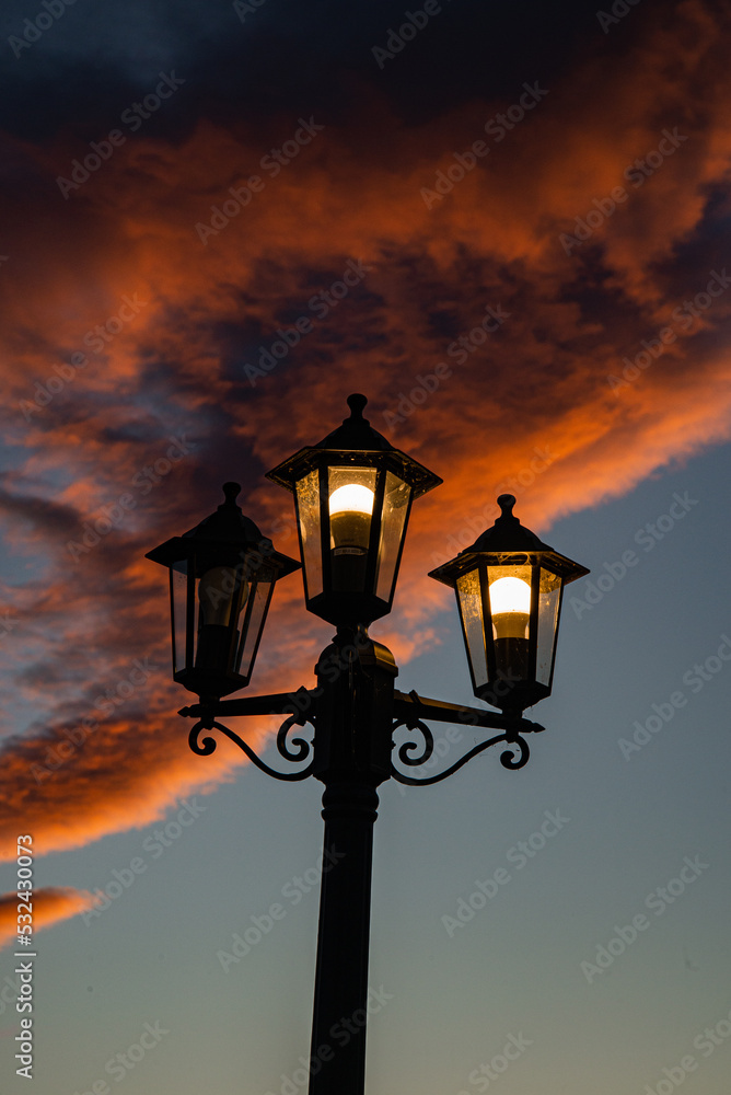 old broken street lamp on a bright orange sunset background