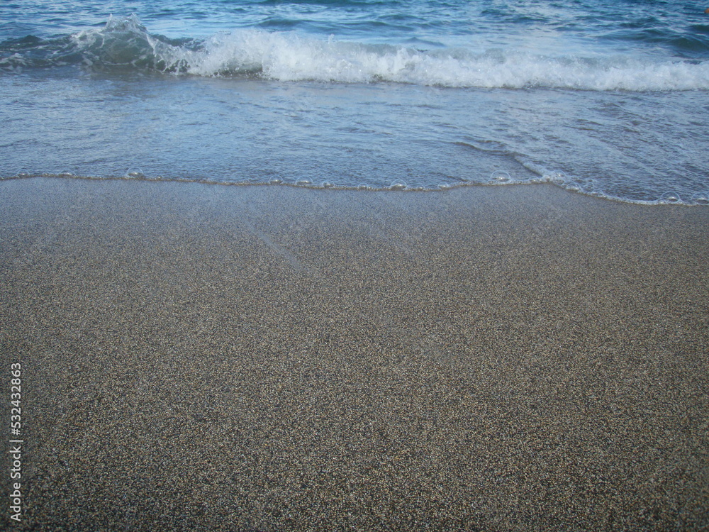 arena de playa recién mojada por el mar en retirada y olas con espuma llegando de nuevo a la orilla arena de playa recién mojada por el mar en retirada y olas con espuma llegando de nuevo a la orilla