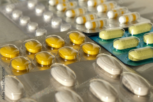 Pile of medical pills in white, yellow and other colors. Pills in plastic packaging. Healthcare and medicine concept.
