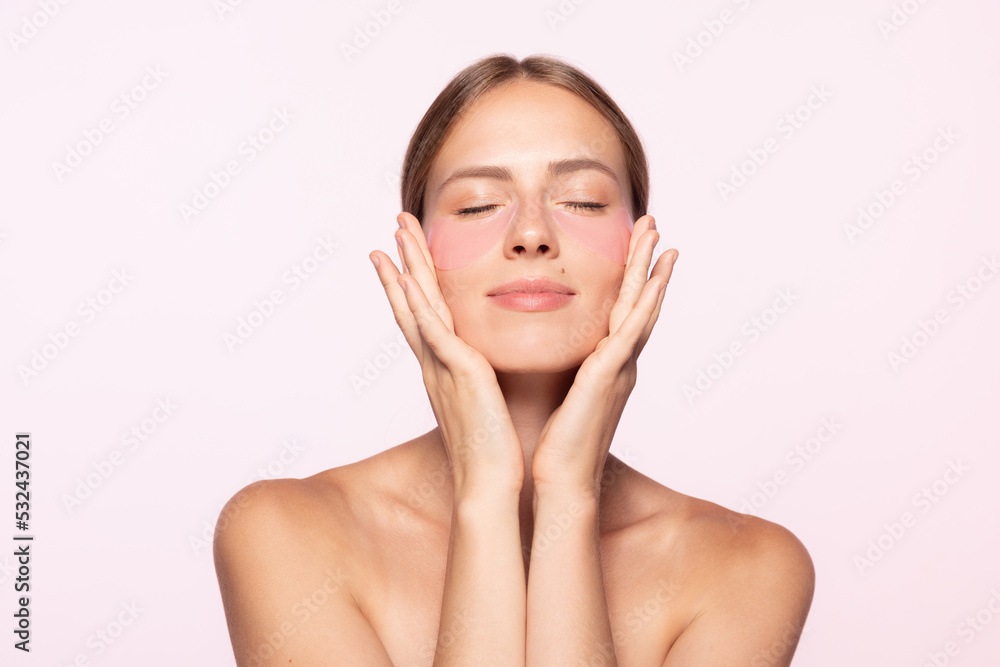 Half-legnth portrait of smiling beautiful girl with naked shoulders applying eye patches isolated over white background Half-legnth portrait of smiling beautiful girl with naked shoulders applying eye patches isolated over white background