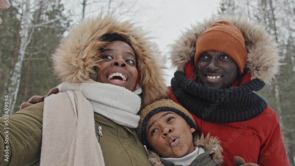 Cheerful Black man, woman and their son spending winter day outdoors on forest park taking selfies on smartphone camera Cheerful Black man, woman and their son spending winter day outdoors on forest park taking selfies on smartphone camera