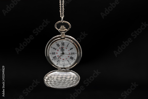 An old pocket watch on black background, copy space