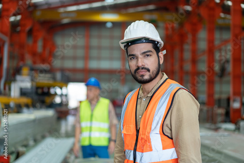 Portrait of man engineer in vest and white helmet safety standing front machine in production line factory.Professional technician look confident working in manufacturing Industrial.