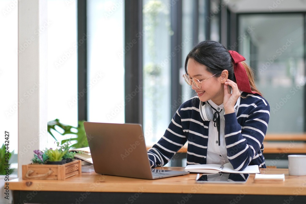 Student learning on laptop indoors- educational course or training, seminar, education online concept, Asian woman with modern laptop and headphones learning at home Student learning on laptop indoors- educational course or training, seminar, education online concept, Asian woman with modern laptop and headphones learning at home