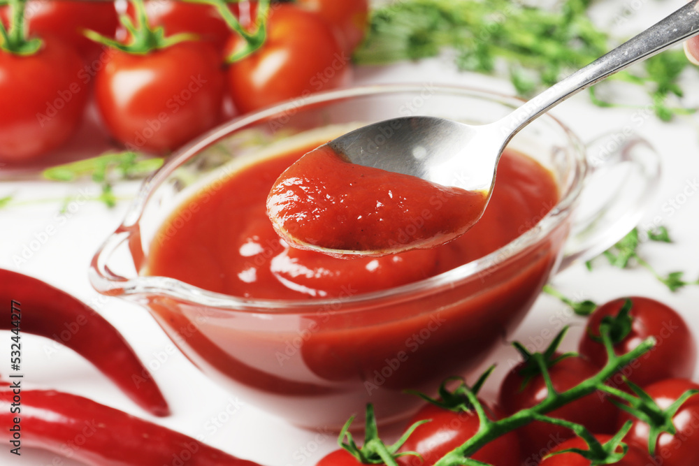 Composition of a gravy boat filled with delicious tomato sauce, a branch of fresh cherry tomatoes, thyme, fresh chilli on a wooden background. Fresh garlic, close-up. Composition of a gravy boat filled with delicious tomato sauce, a branch of fresh cherry tomatoes, thyme, fresh chilli on a wooden background. Fresh garlic, close-up.