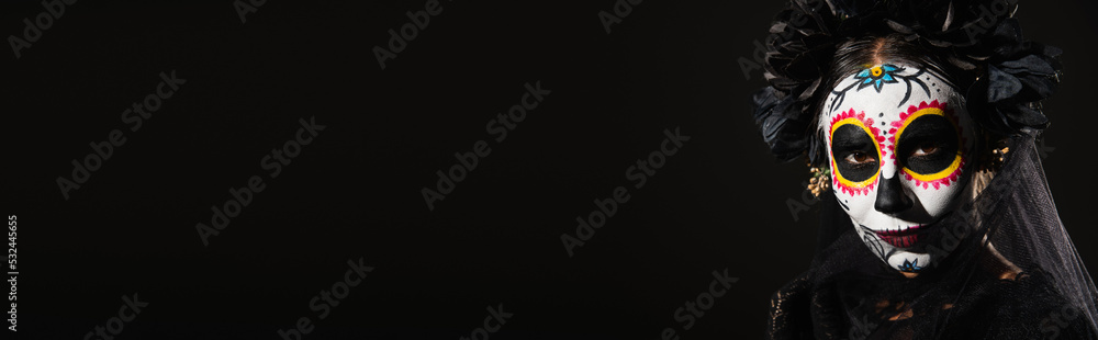 portrait of woman in halloween costume and creepy makeup looking at camera isolated on black, banner.