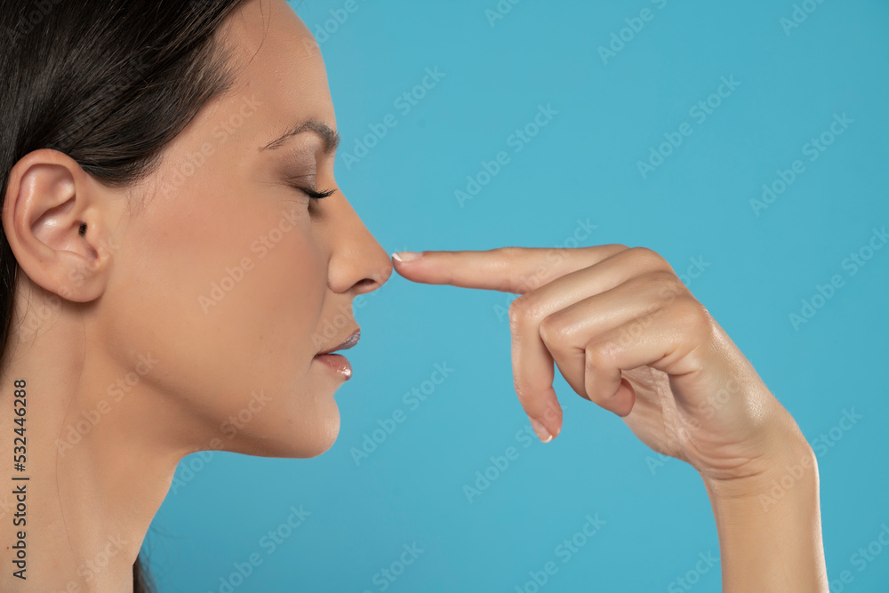 Profile of young woman touching her nose Profile of young woman touching her nose