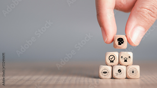 Ethics inside human mind, Business ethics concept. Hand hold ethics inside a head symbols in wooden cubes stacked on gray background with copy space.