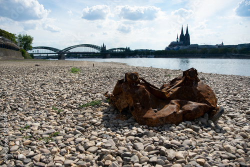 Blick auf den Kölner Dom bei Niedrigwasser, im Vordergrund das trockene Flussbett mit Müll, August 2022. photo