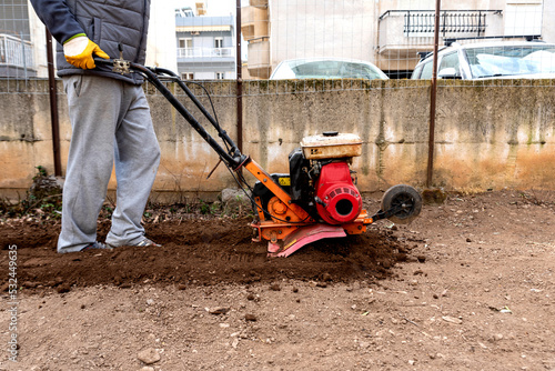 Man weeding with a tiller machine the garden photo