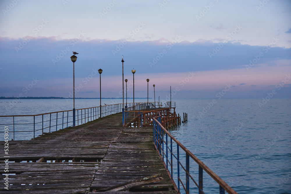 A pier stretching far into the sea against the backdrop of a beautiful sunset.