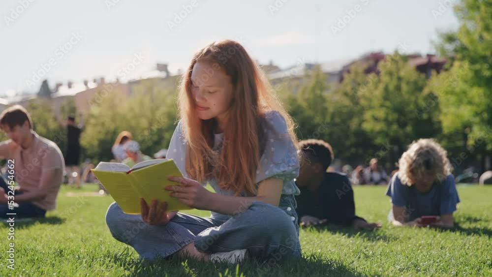 Beautiful teenage girl sitting in park reading book Beautiful teenage girl sitting in park reading book