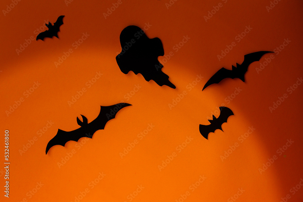 Spooky Halloween. Black ghosts and bats decorations on orange background. Happy Halloween! Trick or treat! space for text
