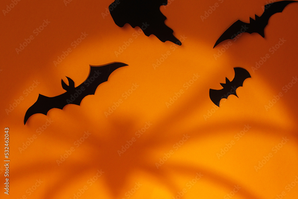 Spooky Halloween. Black ghosts and bats decorations with spider's shadow on orange background. Happy Halloween! Trick or treat! space for text
