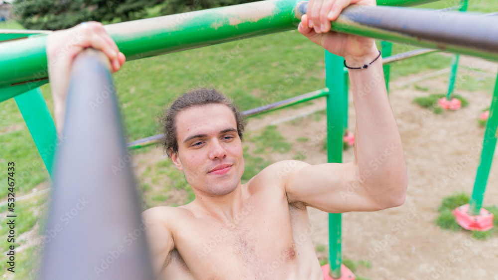 Obraz premium smiling muscular young boy doing exercise n the park.
