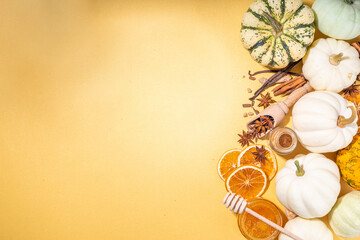Autumn fall pumpkin spice baking and drink ingredients. Various colorful pumpkins, nuts, seasonal spices on golden background. Cooking pumpkin pie, latte, cookies for autumn Thanksgiving holidays