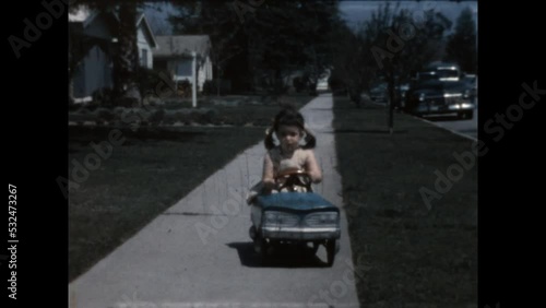 Driving a Toy Car 1965 - A girl drives a toy car on the sidewalk in front of her Canoga Park, California home in 1965. photo