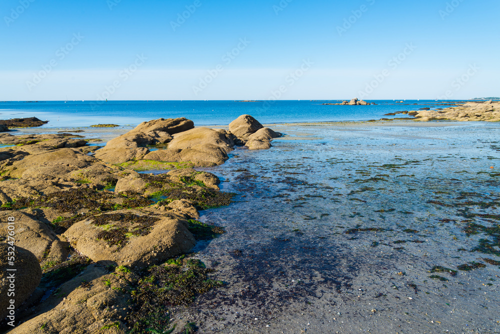 The coastline and beach of Concarneau, Brittany, France, during low tide. Turquoise waters and blue sky on the background.