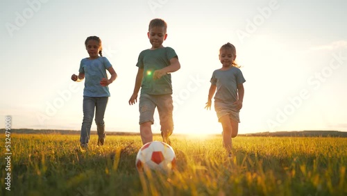 Happy group of children. Kids with soccer ball on green grass. Children play with ball in the park. Kids play and dream on green grass in meadow. Active outdoor recreation in summer. Teamwork in park. photo