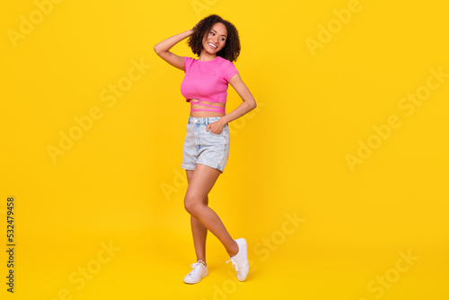 Full body photo of pretty positive girl hand touch hair look empty space isolated on yellow color background