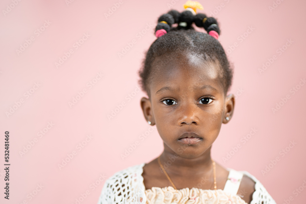 Fototapeta premium Ritratto di una piccola ragazza bella afroamericana isolata con lo sfondo rosa 