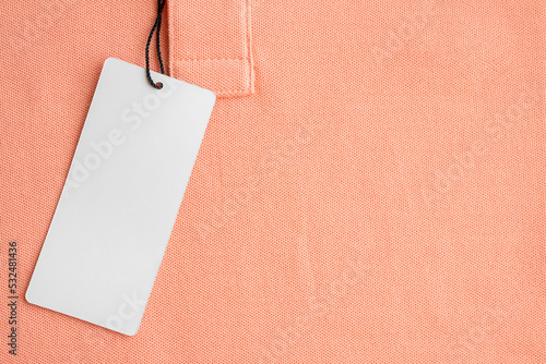 Blank white clothes tag label on pink fabric texture background