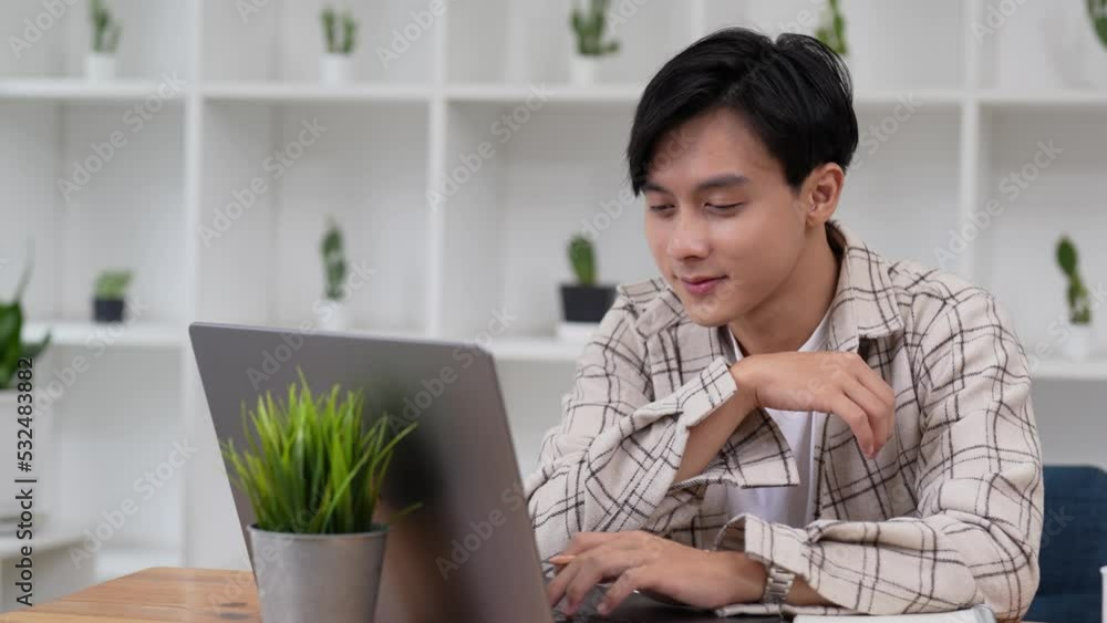 Asian man do remote job from home sit at desk smile enjoy telework activity. Spend time chatting in social networks use laptop, search helpful information for work or study on internet concept. Asian man do remote job from home sit at desk smile enjoy telework activity. Spend time chatting in social networks use laptop, search helpful information for work or study on internet concept.