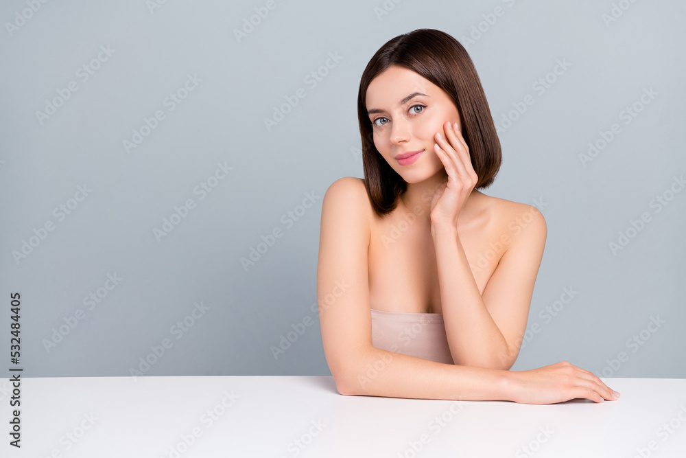 Photo of pretty lady sit table touch cheek hand recommend collagen complexion nourishing isolated over grey color background Photo of pretty lady sit table touch cheek hand recommend collagen complexion nourishing isolated over grey color background
