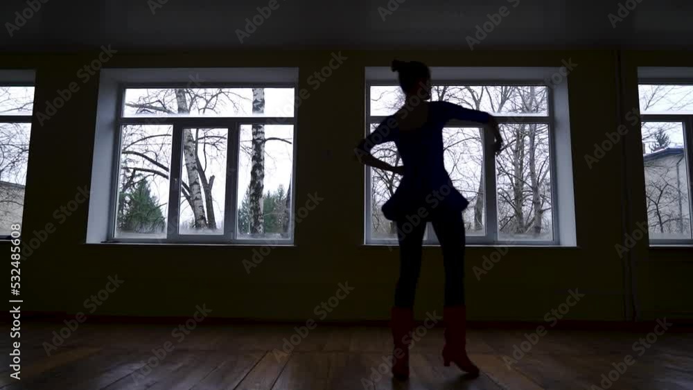 Silhouette of a dancing ballerina training rotation around in the dark classroom Silhouette of a dancing ballerina training rotation around in the dark classroom