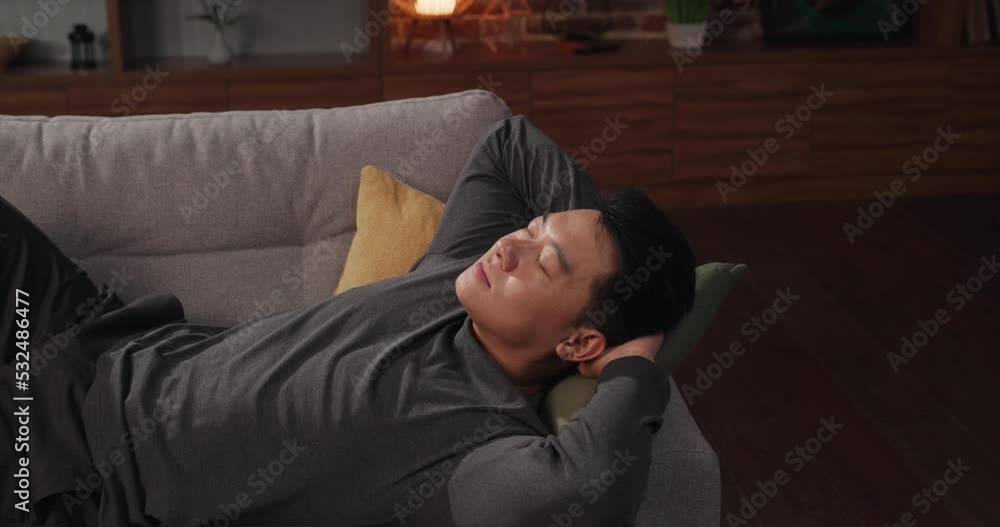 Calm Asian man relaxing on sofa at home after working day Calm Asian man relaxing on sofa at home after working day