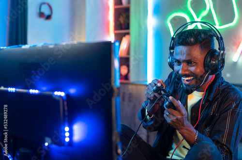 excited pro gamer playing online video game on computer by talking on headphone at home - concept of entertainment, gaming addiction and cyberspace.