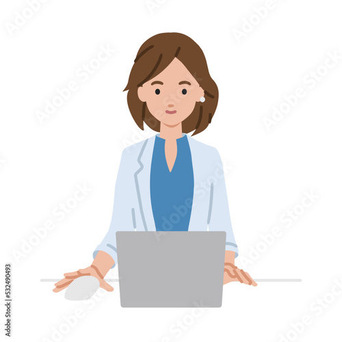 デスクで座ってPCを使っているジャケットの女性