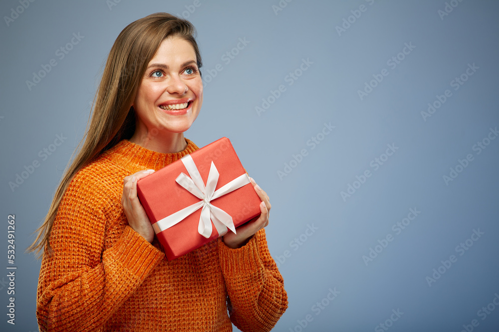 Portrait happy woman looking side away with present gift box isolated on blue background. Portrait happy woman looking side away with present gift box isolated on blue background.