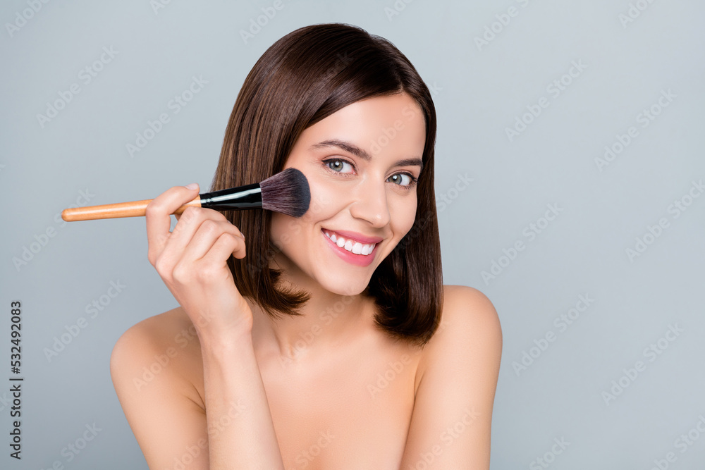 Photo of joyful lady look mirror use applicator brush prepare date party isolated over grey color background Photo of joyful lady look mirror use applicator brush prepare date party isolated over grey color background