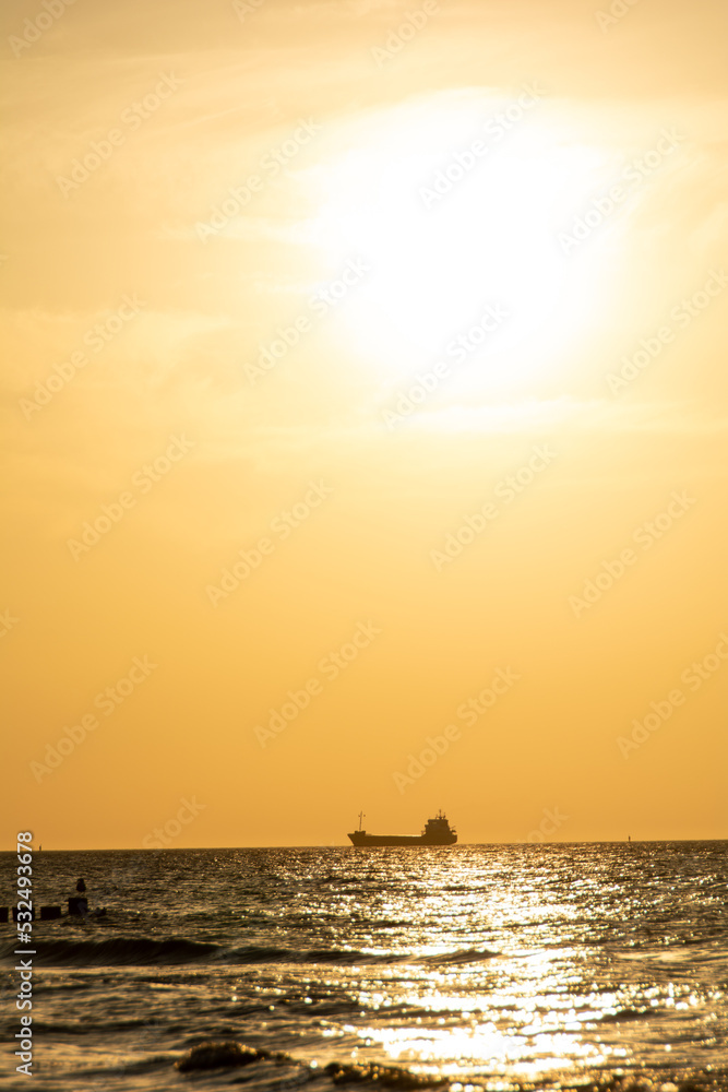 Sunset over the sea with a ship on the horizon