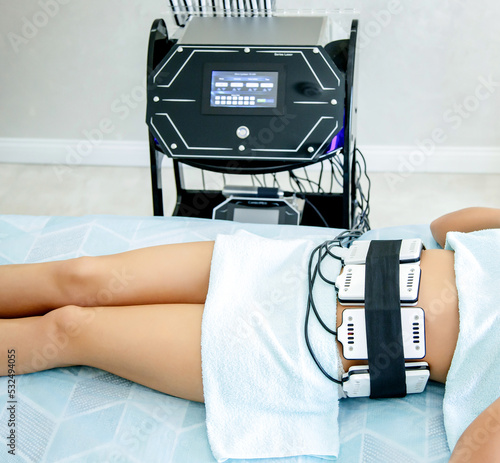 In a beauty salon, a girl performs a hardware procedure for weight loss laser lipolysis. Figure correction by hardware methods
