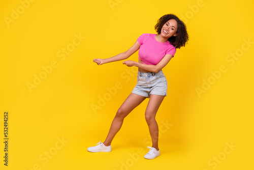Full length profile photo of funky carefree girl hands pull empty space rope isolated on yellow color background