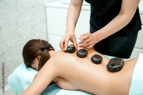 The girl is lying on the stone massage procedure in the spa center. Relaxation and recovery in the beauty clinic