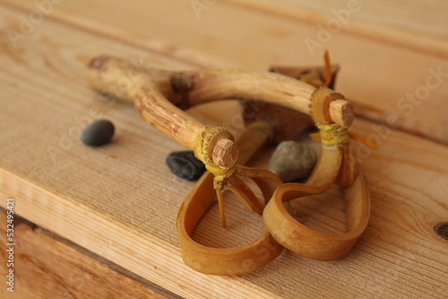 A wooden craft slingshot with some rocks and pebbles