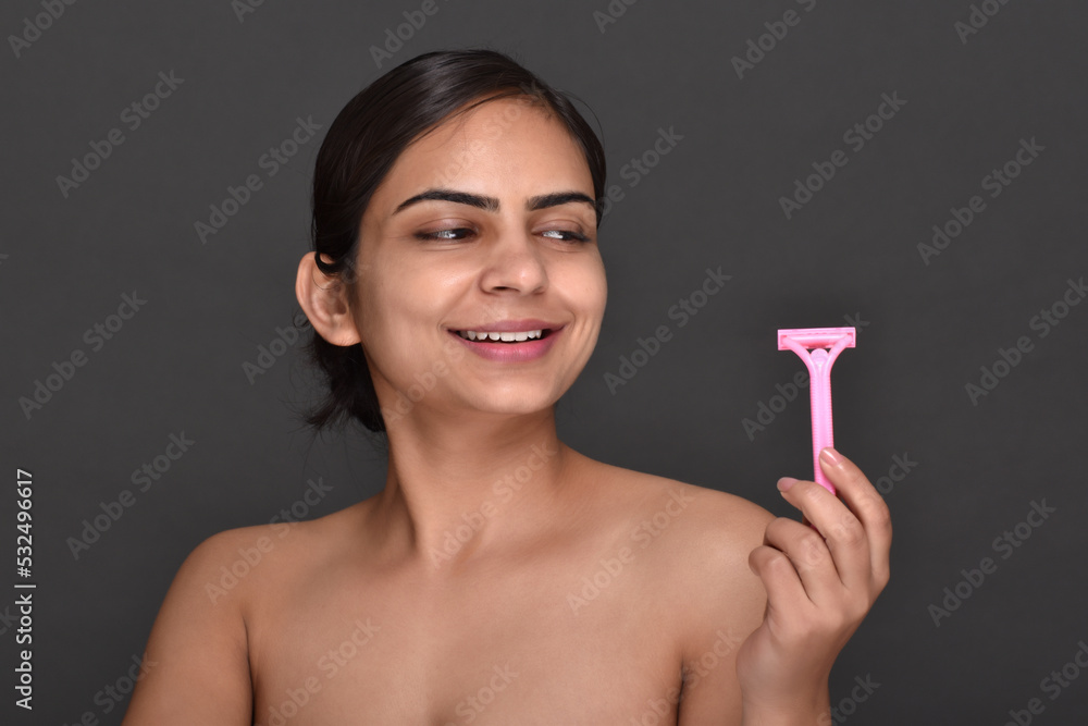 A young woman with clear,spotless skin holding a hair removal razor A young woman with clear,spotless skin holding a hair removal razor
