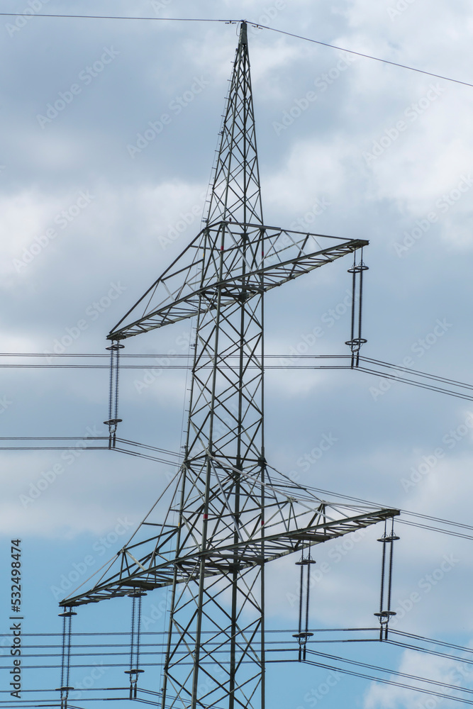 Electricity pylon for over land power transmission of high voltage in front of blue sky