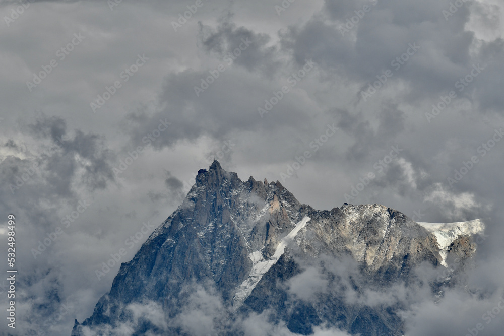 The Aiguille du Midi in the middle of dramatic clouds. This is a 3,842-metre-tall (12,605 ft) mountain in the Mont Blanc massif within the French Alps. It is a popular tourist destination
