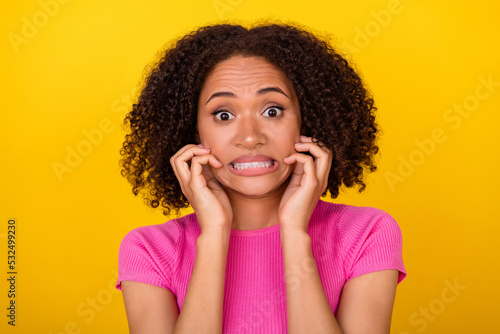 Portrait of worried unsatisfied girl hands touch face grin teeth look camera isolated on yellow color background