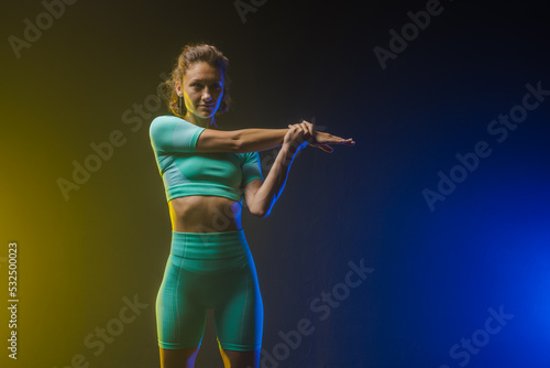 the girl trains on a dark background, modern fitness on a yellow-blue background with a place for text
