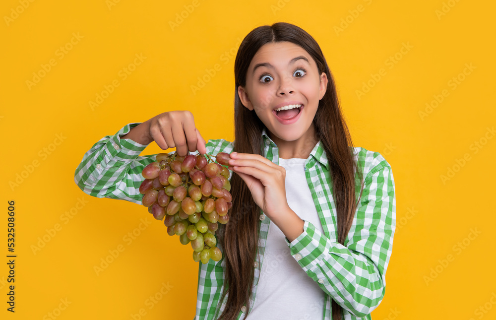 amazed teen girl with grapes fruit on yellow background amazed teen girl with grapes fruit on yellow background