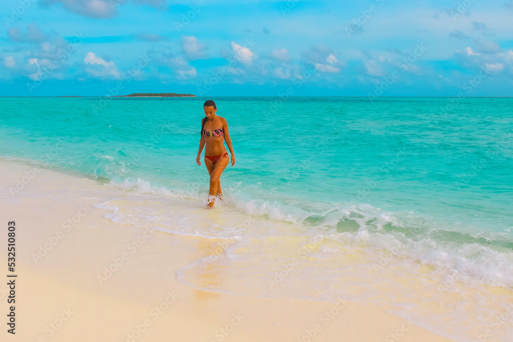 Young adult woman walking from the ocean. The waves of the sea touching her legs and feat. Young adult woman walking from the ocean. The waves of the sea touching her legs and feat.